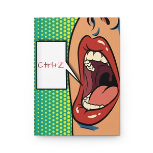 May include: A rectangular notebook featuring a pop art illustration of an open mouth with red lips and white teeth. A white speech bubble contains the red text Ctrl+Z. The background is a teal and yellow dot pattern in a comic book style.