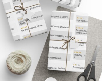 May include: White wrapping paper featuring a repeating pattern of five-star reviews and text including "Tears of joy," "Low-key obsessed," and "Everything wrap looks rich now." The paper is tied with brown twine and star-shaped gift tags.