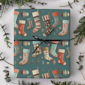 Puede incluir: Un regalo rectangular envuelto en papel verde azulado con un patrón repetitivo de calcetines navideños de estilo retro en tonos rojo, rosa, marrón y azul, acentuado con estrellas y diamantes, atado con una cinta negra delgada.
