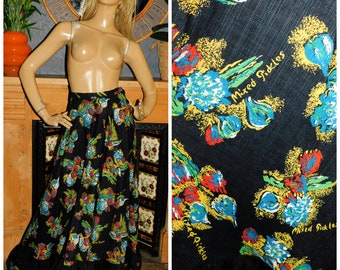 May include: A black maxi skirt with a colourful floral print. The print features blue, yellow, red, and green flowers and the words "Mixed Pickles" repeated throughout. The skirt has a ruffled hem.