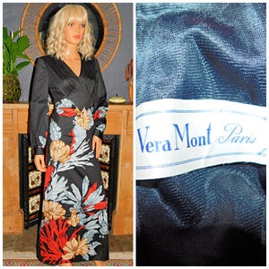 May include: A black maxi dress with a floral print. The dress has a V-neckline and long sleeves. The dress is made of a soft, flowing fabric. The dress has a label that says "Vera Mont Paris".