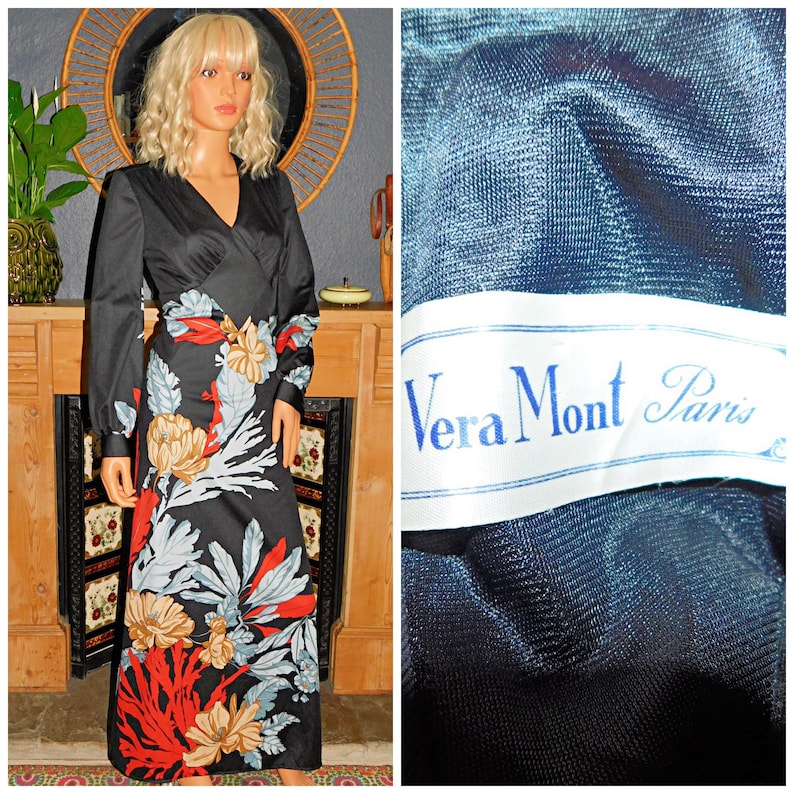 May include: A black maxi dress with a floral print. The dress has a V-neckline and long sleeves. The dress is made of a soft, flowing fabric. The dress has a label that says "Vera Mont Paris".