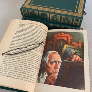 May include: An open book with an illustration of an elderly man painting. The book is titled "The Way of All Flesh" and is bound in dark green leather with gold detailing. Two more books are stacked behind it.