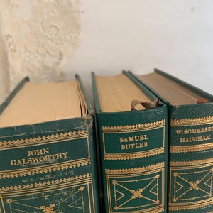May include: Three vintage hardcover books with green covers and gold lettering. The spines display author names: John Galsworthy, Samuel Butler, and W. Somerset Maugham. Decorative gold patterns adorn the covers.