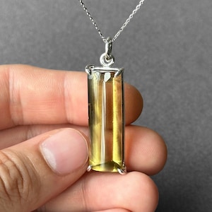 Könnte beinhalten: Eine silberne Kettenkette mit einem rechteckigen Anhänger in Gelb und Klar. Der Anhänger ist in einer silbernen Fassung gefasst.