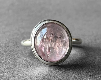May include: A silver ring with a pink gemstone set in a bezel setting.