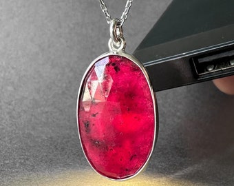 Op de afbeelding: Een zilveren ketting met een grote, ovale, gefacetteerde, roze edelsteen hanger.