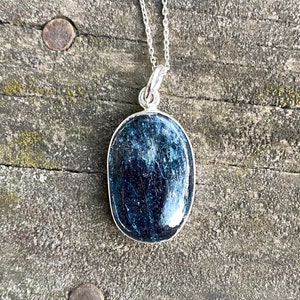 Peut inclure: Un collier en argent avec un pendentif ovale bleu fonc&eacute;. Le pendentif est fait d'une pierre naturelle avec un motif unique.