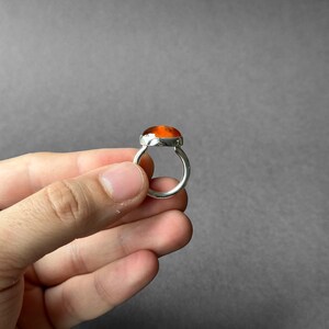 May include: A silver ring with an orange gemstone set in a bezel setting.