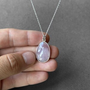 May include: A silver chain necklace with a light pink faceted gemstone pendant.