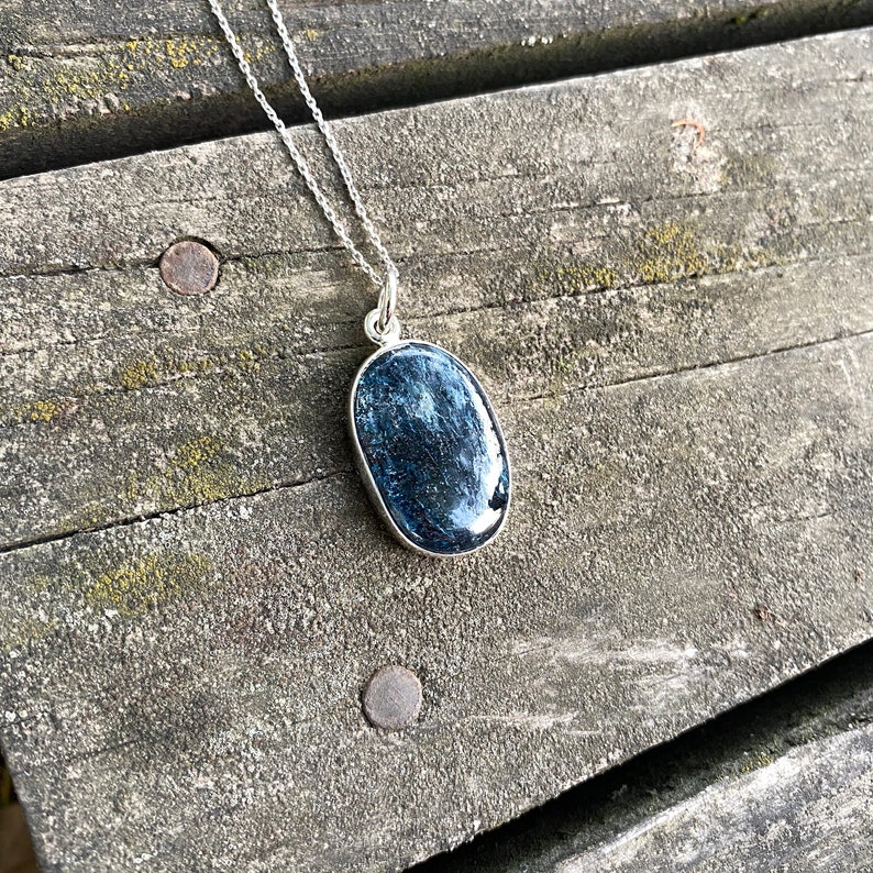 Peut inclure: Un collier en cha&icirc;ne argent avec un pendentif ovale bleu orn&eacute; d'une pierre textur&eacute;e scintillante.