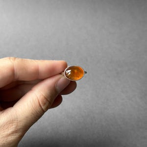 May include: A silver ring with an oval-shaped amber gemstone. The ring is set in a simple band.