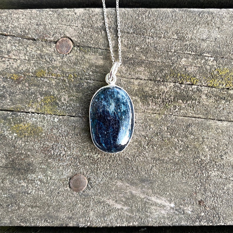 Peut inclure: Un collier en argent avec un pendentif ovale bleu fonc&eacute;. Le pendentif est fait d'une pierre naturelle avec un motif unique.