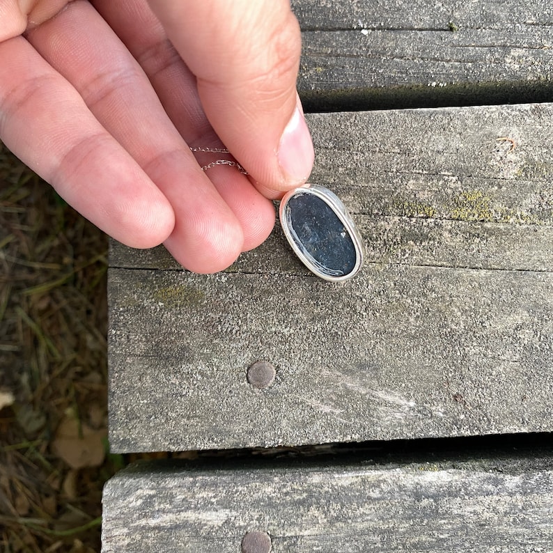 Peut inclure: Un collier en cha&icirc;ne argent avec un pendentif ovale noir.