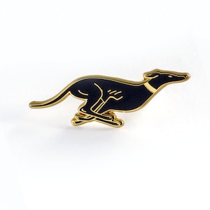May include: Gold-coloured enamel pin featuring a black silhouette of a running greyhound.