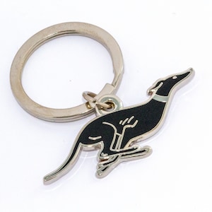 Peut inclure: Un porte-clés en métal argenté avec un motif de chien lévrier noir et argent. Le chien est représenté en pleine course, avec un collier argenté. L'anneau du porte-clés est également argenté.