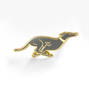 May include: A gold-coloured enamel pin featuring a grey silhouette of a running greyhound.