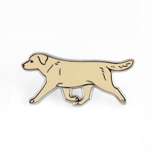 May include: A yellow Labrador Retriever running to the right, depicted in a cartoon style enamel pin.