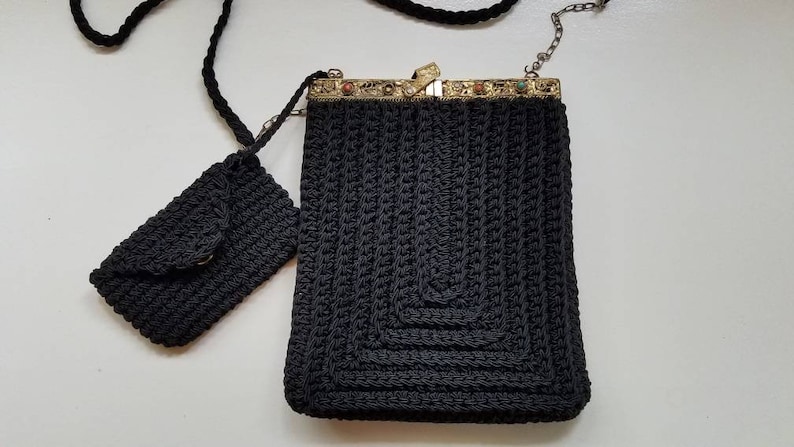 Puede incluir: Un bolso de crochet negro con cierre de metal y un bolso m&aacute;s peque&ntilde;o a juego. El bolso tiene una correa de cadena.