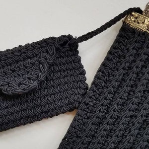 Puede incluir: Dos bolsos de crochet negros, uno con un cierre de metal y un acento de piedra roja. El bolso m&aacute;s peque&ntilde;o tiene un cierre de solapa.