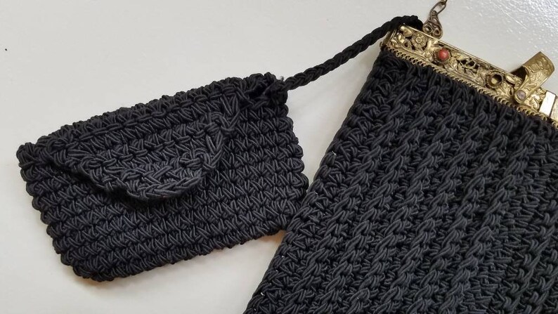 Puede incluir: Dos bolsos de crochet negros, uno con un cierre de metal y un acento de piedra roja. El bolso m&aacute;s peque&ntilde;o tiene un cierre de solapa.