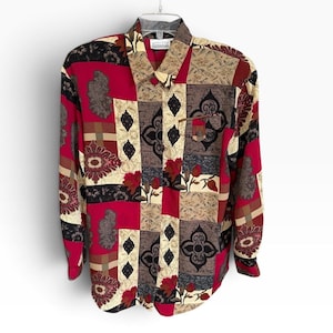 May include: A long-sleeve button-down shirt featuring a patchwork design with alternating blocks of deep red, cream, and dark brown. The pattern includes floral motifs, paisley shapes, and geometric ornaments, with a small chest pocket on the right side.