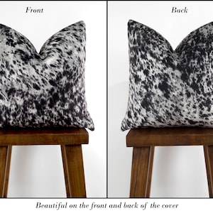 May include: Black and white cowhide patterned pillow cover. The pillow cover is shown on the front and back, with the pattern visible on both sides.