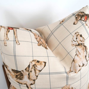 Peut inclure: Un oreiller beige avec un motif &agrave; carreaux bleu et blanc et une illustration r&eacute;p&eacute;t&eacute;e de chiens bruns et blancs.