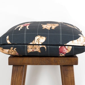 Peut inclure: Un coussin en tissu noir et blanc &agrave; carreaux avec un motif r&eacute;p&eacute;t&eacute; de chiens dans diff&eacute;rentes poses. Le coussin est pos&eacute; sur un tabouret en bois.