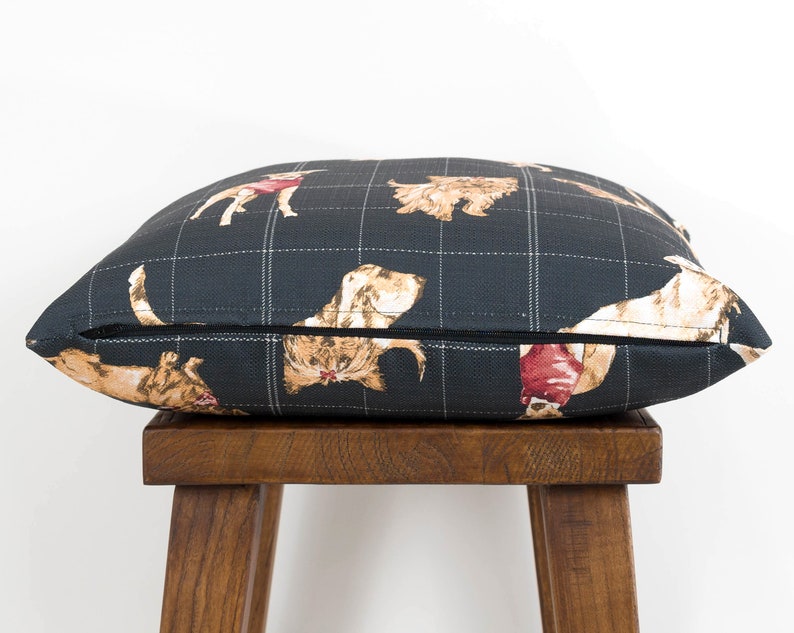 Peut inclure: Un coussin en tissu noir et blanc &agrave; carreaux avec un motif r&eacute;p&eacute;t&eacute; de chiens dans diff&eacute;rentes poses. Le coussin est pos&eacute; sur un tabouret en bois.