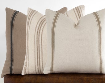 May include: Three decorative throw pillows with brown and white striped patterns. The pillows are made of a soft, textured fabric and are perfect for adding a touch of farmhouse style to any room.
