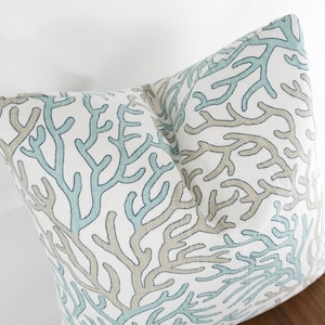 Puede incluir: Una almohada blanca con un patr&oacute;n de arrecife de coral azul y marr&oacute;n. La almohada est&aacute; hecha de una tela suave y c&oacute;moda y es perfecta para agregar un toque de estilo costero a tu hogar.