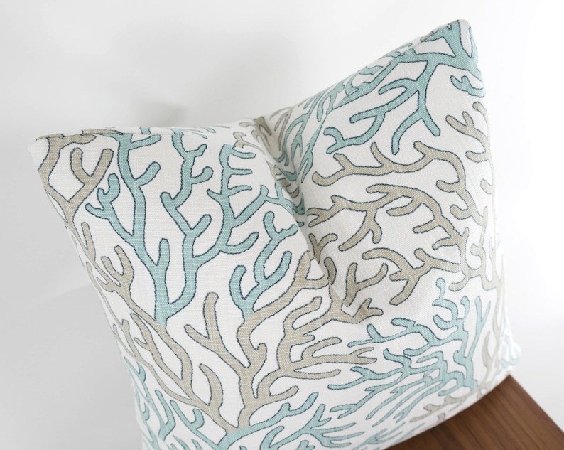 Puede incluir: Una almohada blanca con un patr&oacute;n de arrecife de coral azul y marr&oacute;n. La almohada est&aacute; hecha de una tela suave y c&oacute;moda y es perfecta para agregar un toque de estilo costero a tu hogar.