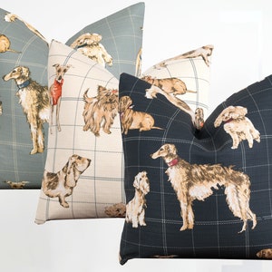 Peut inclure: Trois coussins d&eacute;coratifs avec un fond &agrave; carreaux et un motif r&eacute;p&eacute;t&eacute; de chiens de diff&eacute;rentes races. Les coussins sont dans des tons de gris, beige et noir.