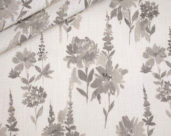 May include: Floral fabric with a watercolor-style design. The pattern features gray flowers and foliage on a light beige background. The fabric is folded over, showing the texture and pattern repeat.