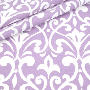 May include: Close-up of a folded fabric with a repeating white floral pattern on a lavender background. The fabric has a soft texture and a classic design, suitable for various home decor projects.