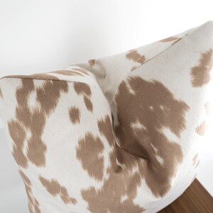 May include: A white and brown patterned throw pillow with a soft, plush texture.