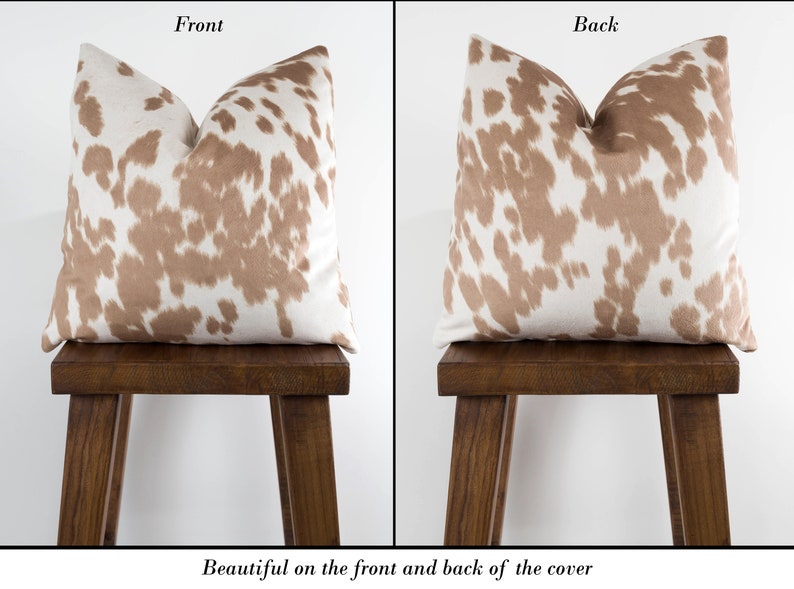 May include: A brown and white cowhide patterned pillow cover. The pattern is visible on both the front and back of the pillow cover.