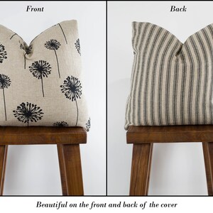 May include: A decorative pillow with a black dandelion print on the front and black and white stripes on the back. The pillow is sitting on a wooden stool.