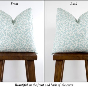 May include: A light blue pillow cover with a white floral pattern. The pillow is shown on the front and back, demonstrating the pattern is the same on both sides.