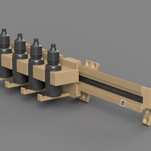 Puede incluir: Un soporte de pared impreso en 3D de color beige con cinco ranuras para sujetar botellas. El soporte tiene una etiqueta negra que dice "Dos imanes de neodimio de 10x10 mm van aquí." y un logotipo que dice "TENTACLE CREATIONS".