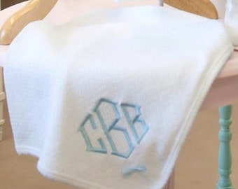 May include: A white baby blanket with a light blue embroidered monogram of the letters "CBB".