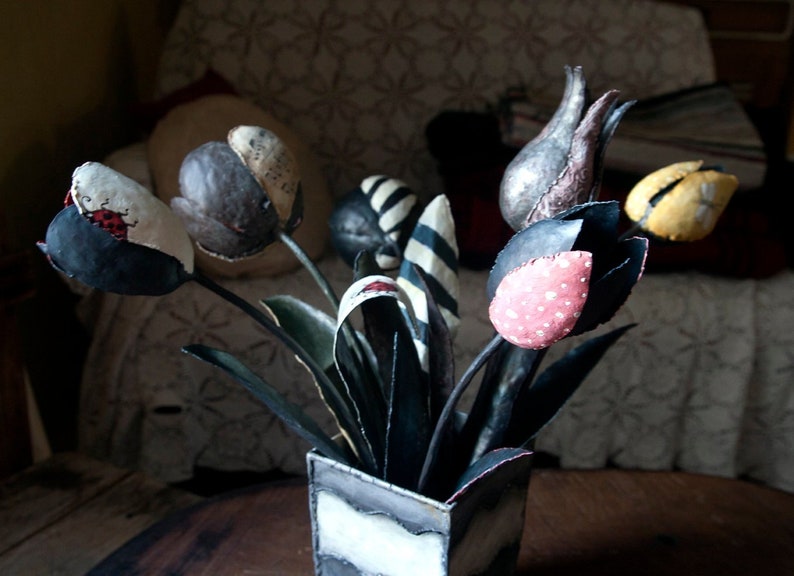 May include: A bouquet of fabric tulips in a black and white vase. The tulips are made of different fabrics and have various patterns, including polka dots, stripes, and floral designs.