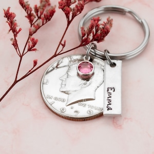 May include: Silver keychain with a 1979 half dollar coin, a pink rhinestone, and a silver tag engraved with the name "Emma".