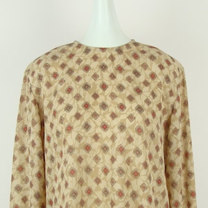 May include: A beige long-sleeved blouse with a geometric pattern in shades of red, brown, and gray.