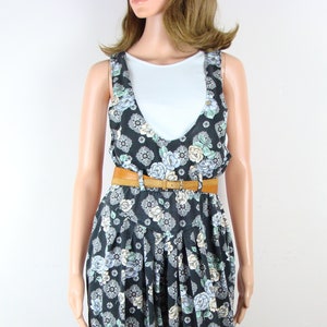 May include: A black and white floral print jumpsuit with a brown belt. The jumpsuit has a sleeveless design and a wide-leg silhouette.