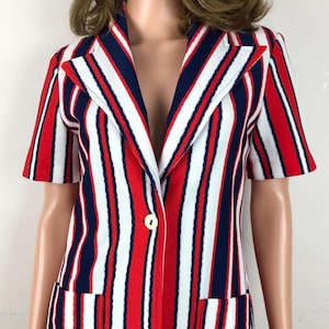 May include: A red, white, and blue striped short-sleeved blazer with a single button closure and two pockets.