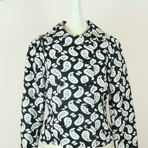 May include: A black and white paisley patterned jacket with a double breasted closure and black buttons.