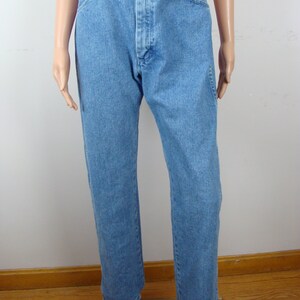 May include: Light blue denim jeans with a brown leather belt. The jeans have a classic five-pocket design and a straight leg cut. The belt has a silver buckle and a series of decorative cutouts.