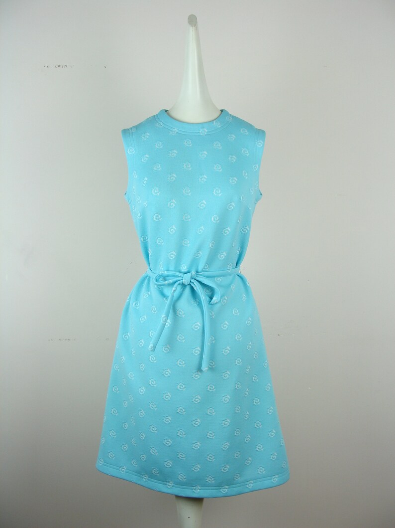 Może przedstawiać: Bezrękawowa jasnoniebieska sukienka z białym wzorem kwiatowym i pasującym paskiem do wiązania.